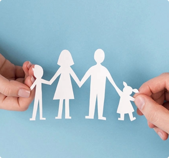 Sagoma di carta raffigurante una famiglia con due adulti e due bambini, tenuta tra due mani.