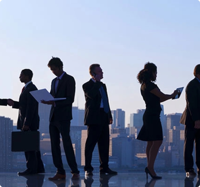 Persone in abiti da lavoro interagiscono su uno sfondo cittadino al tramonto.